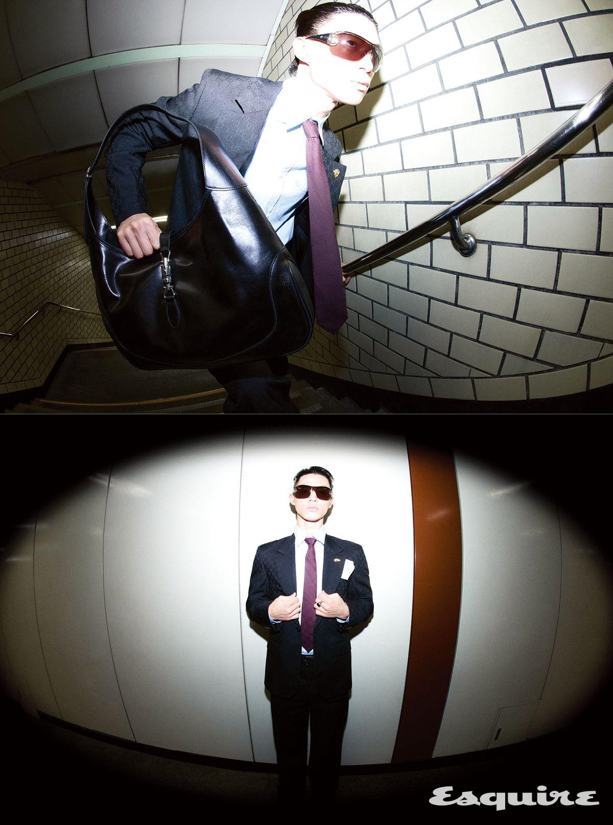 구찌 크레스트 브로치 디테일의 싱글브레스티드 GG 울 재킷, 포플린 셔츠, 울 팬츠, 코튼 자카르 타이, 블랙 레더 구찌 재키 1961 라지 백, 구찌 크레스트 시넷 링, 실크 포켓 스퀘어 모두 구찌. 선글라스 구찌 by 케어링 아이웨어.