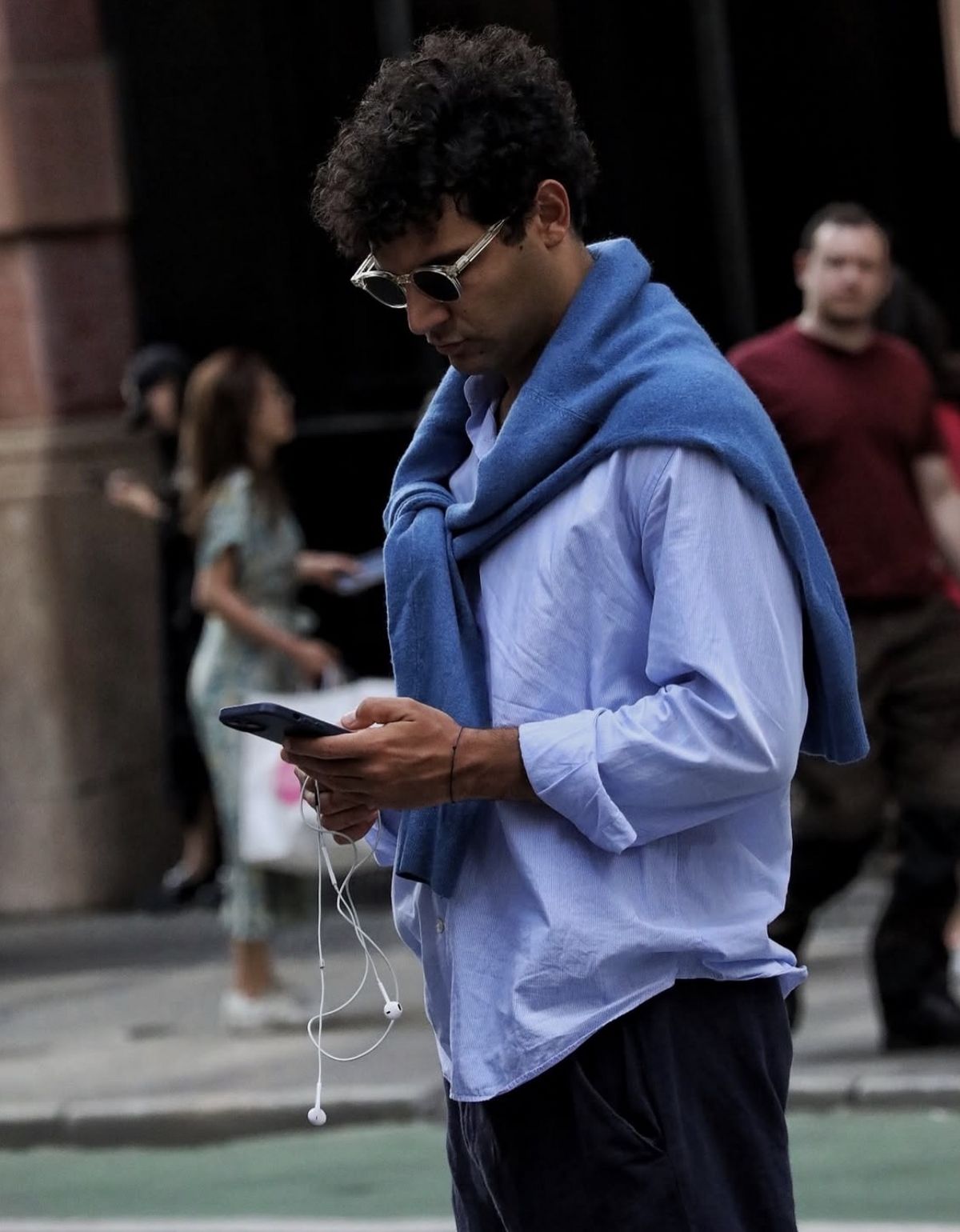 짙은 블루 컬러의 스웨터를 어깨에 무심하게 걸치고, 줄 이어폰과 안경과 같은 소품을 사용하여 퍼포머티브 메일 룩을 완성했다. / 이미지 출처: 인스타그램 @meninsoho