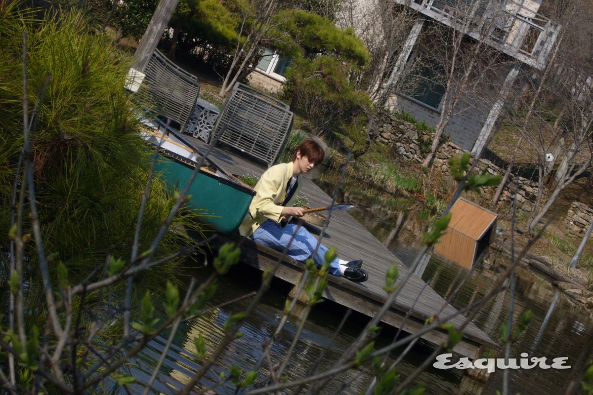 작은 배 앞에서 물을 바라보는 플레어 유 우진.