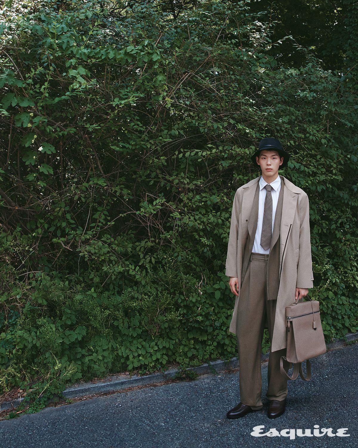 베이지 트렌치코트, 브라운 더블브레스티드 슈트, 스트라이프 셔츠, 카프 레더 세르지오 워크 로퍼, 블랙 캐시미어 노아 해트, 브라운 예일 타이, 브라운 레더 엑스트라 백팩 모두 로로피아나.