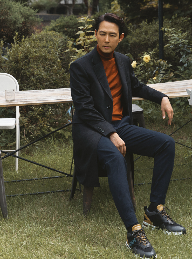  오렌지 컬러 터틀넥 니트, 브라운 블루 컬러 코트, 조거 트라우저, 체사레 스니커즈 모두 에르메네질도 제냐.