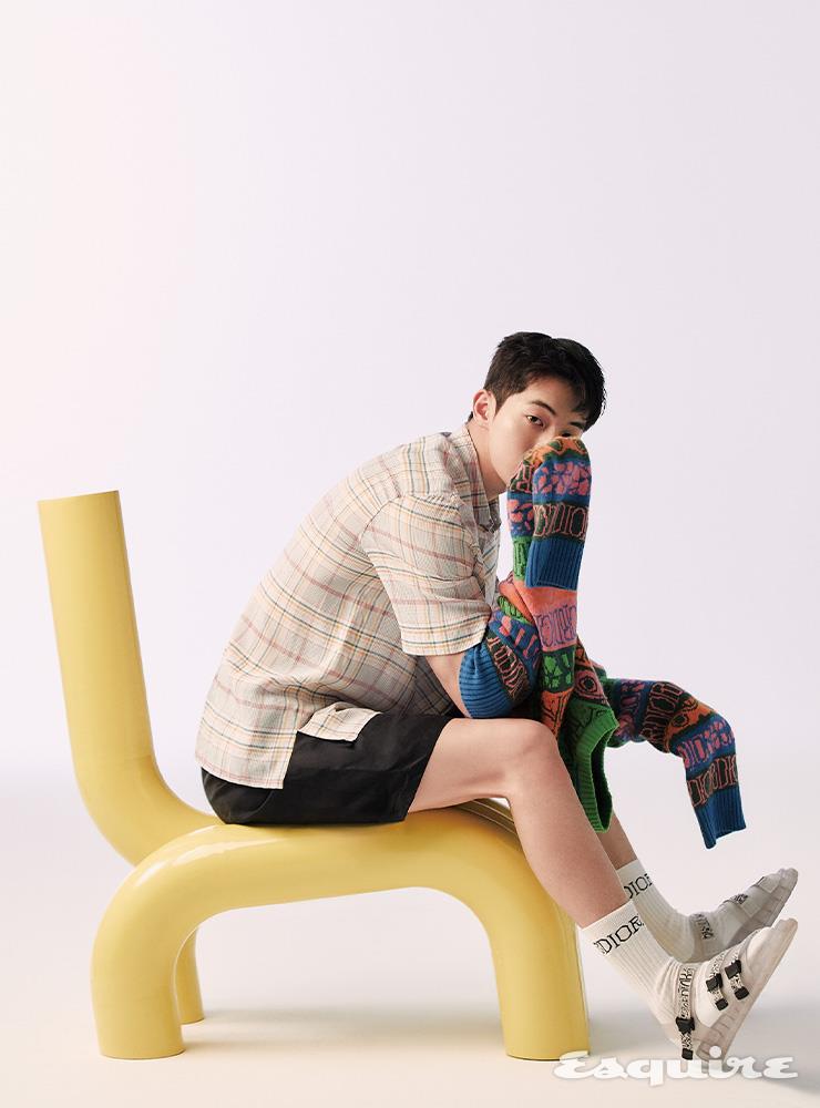 멀티컬러 캐시미어 니트, 오간자 소재 체크 반소매 셔츠, 네이비블루 버뮤다 쇼츠, 화이트 삭스, 반투명 솔을 단 아쿠아 샌들 모두 디올 맨. 노란색 의자 스툴 365.