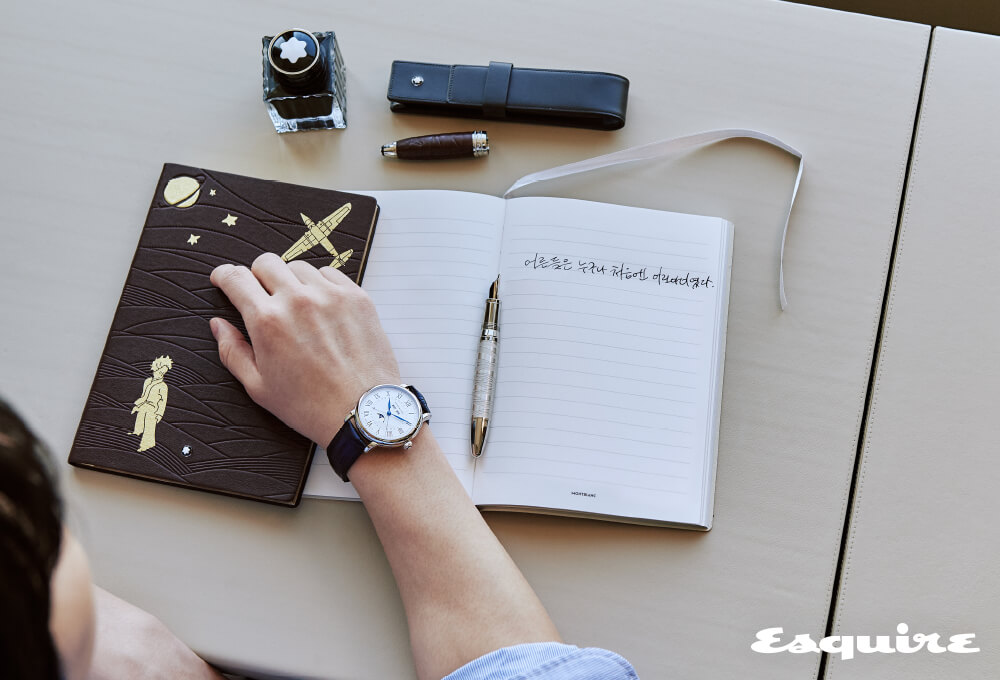 문페이즈와 월, 일, 요일 인디케이터를 탑재한 로마숫자 인덱스의 ‘스타 레거시 풀 캘린더’ 568만원, 갈색 가죽 커버에 소설 속 삽화를 골드 포일 디테일로 더한 ‘르 쁘띠 프린스 에비에이터 유선 노트’ 10만원, 갈색 ‘르 쁘띠 프린스 샌드 오브 더 데저트’ 병 잉크 50ml/4만9000원, 유러피안 풀 그레인 카우하이드 소재의 ‘마이스터스튁 펜 파우치’ 20만원, 속 사막과 비행사의 비행기 이미지가 엠보싱 처리된 갈색 가죽 캡의 ‘마이스터스튁 르 쁘띠 프린스 솔리테어 듀에 만년필’ 223만원 모두 몽블랑. 셔츠 라르디니.