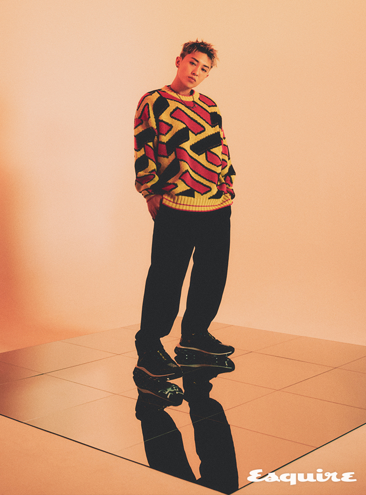 옐로 그래픽 프린트 니트 톱, 블랙 그래픽 프린트 팬츠, 블랙 스니커즈, 네크리스 모두 베르사체.