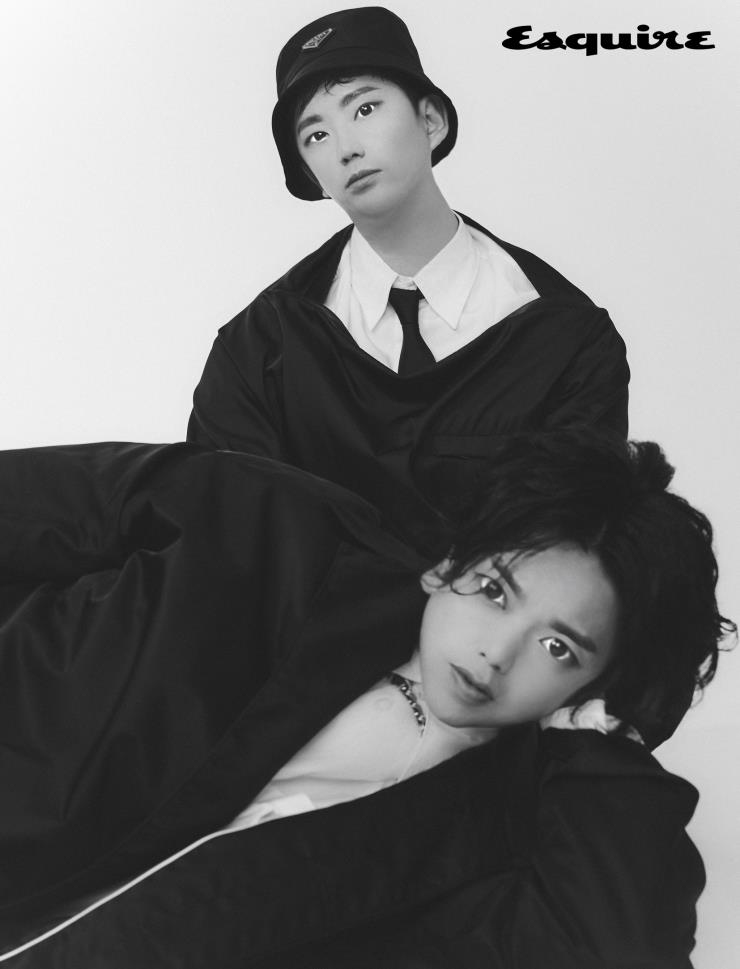 제이호 | 블랙 나일론 톱, 화이트 셔츠, 블랙 타이, 버킷 해트 모두 프라다. 탄 | 블랙 나일론 코트, 화이트 셔츠 모두 프라다. 골드 네크리스 에디터 소장품. 