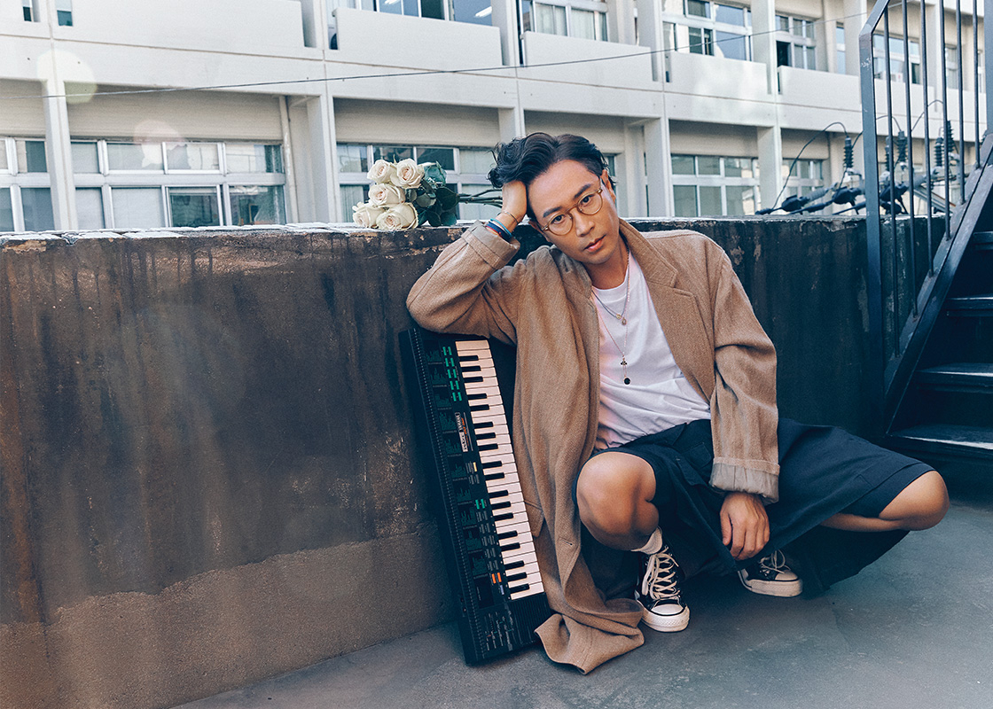 브라운 코트 언유즈드. 블랙 쇼츠 꼼데가르송. 블랙 하이톱 스니커즈 컨버스. 네크리스 모두 수엘. 화이트 티셔츠, 안경, 삭스, 브레이슬릿 모두 스타일리스트 소장품.
