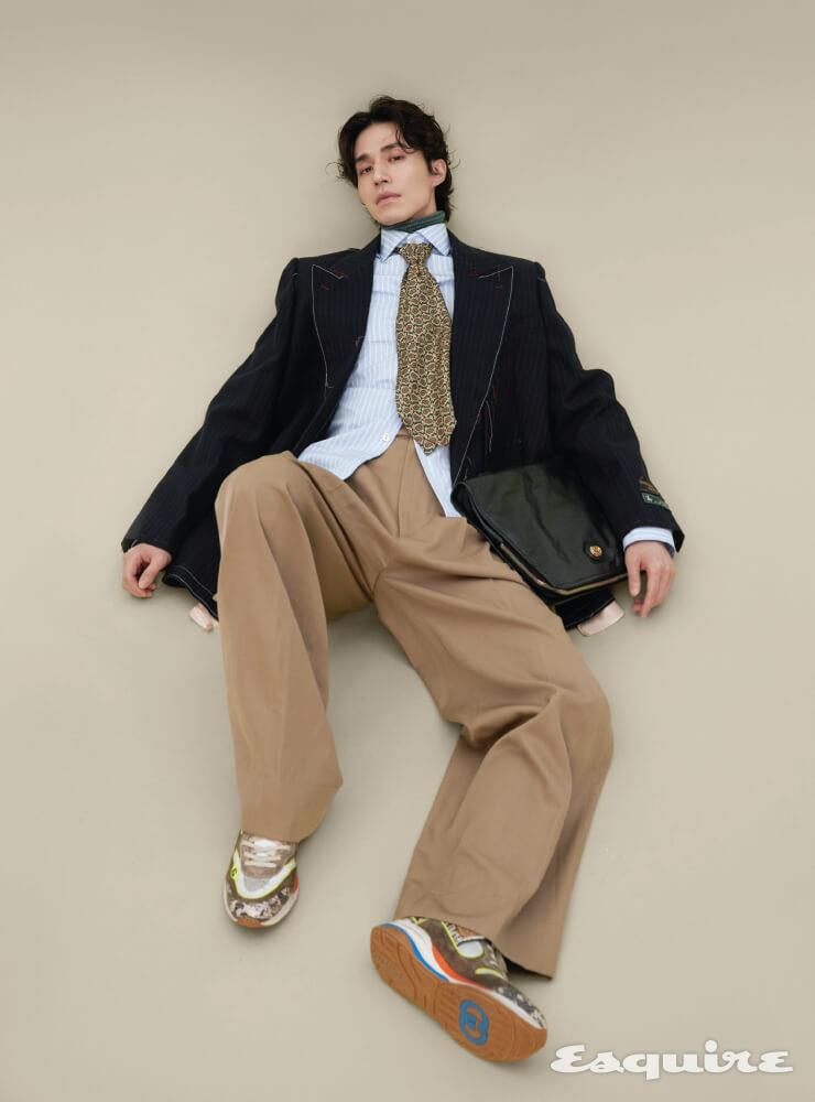  핀스트라이프 재킷, 스트라이프 울 터틀넥 니트, 스트라이프 셔츠, 울 새틴 팬츠, 다양한 구찌 로고 디테일과 멀티컬러가 조화된 울트라페이스 스니커즈, 인터로킹 G 디테일이 특징인 소프트 레더 포트폴리오. 페이즐리 프린트 타이 모두 구찌.