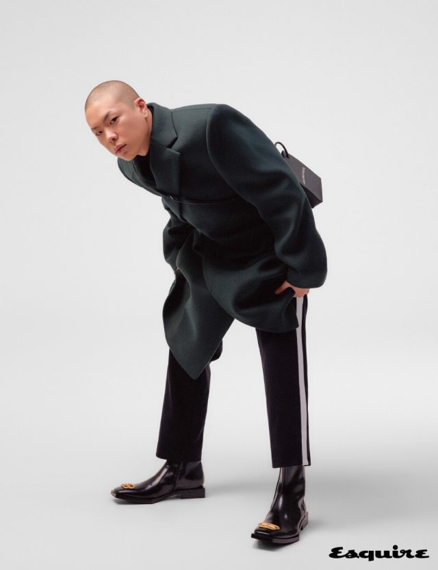 건축적인 실루엣의 시프티드 코트, 터틀넥 톱, 트랙 슈트 팬츠, BB 로고 장식의 부티, 콤팩트한 사이즈의 폰 홀더 백 모두 발렌시아가.