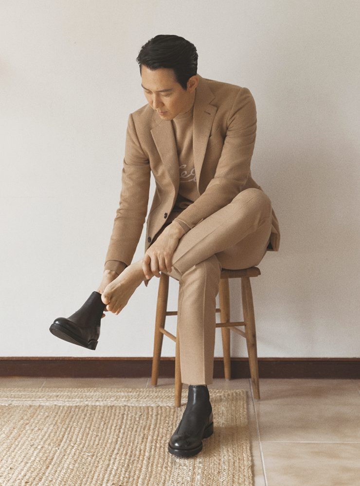 낙타털 소재의 캐멀 컬러 재킷, 캐멀 컬러 트라우저, 로고 장식의 캐시미어 니트, 블랙 첼시 부츠 모두 에르메네질도 제냐. 