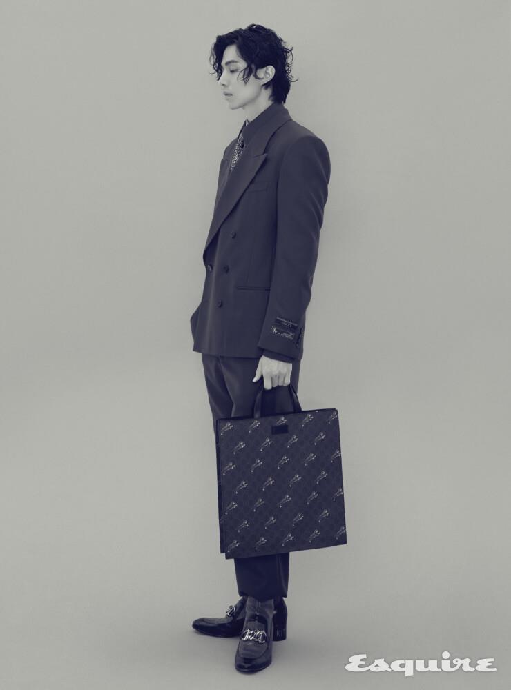  밀리터리풍 테일러드 재킷, 셔츠, 스트라이프 셔츠, 밀리터리풍 팬츠, 체인 호스빗 디테일의 리저드 가죽 소재 부티, 페이즐리 프린트 타이, 호랑이 프린트와 웹 스트랩의 소프트 GG 슈프림 토트백 모두 구찌.