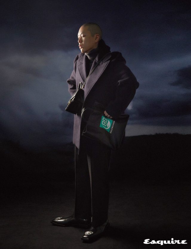 하우스의 아이코닉 코쿤 실루엣에서 영감받은 구조적인 핀치드 피코트, 회색 터틀넥 톱, 크롭트 팬츠, BB 로고 장식 부티, 그린 로고 마켓 토트백, 유려한 곡선 실루엣과 메탈 소재의 B 모양 잠금 장치가 만나 유니크한 아워글래스(hourglass) 스몰 사이즈 백 모두 발렌시아가.