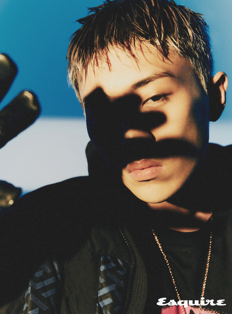 블랙 그래픽 포인트 패딩 재킷, 블랙 메두사 프린트 티셔츠, 블랙 레더 글로브, 네크리스 모두 베르사체.