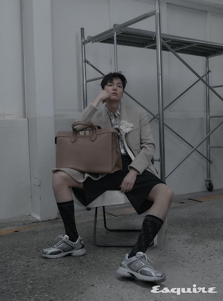 캐시미어 코트, 펜디 오’락 체인 모노그램 프린트 실크 셔츠, 울 버뮤다 팬츠, 펜디 패스터 스니커즈, 피카부 아이씨유 포티 8 백, FF 모티브 삭스, 크리스털 및 펄 장식 플라워 브로치 모두 펜디.