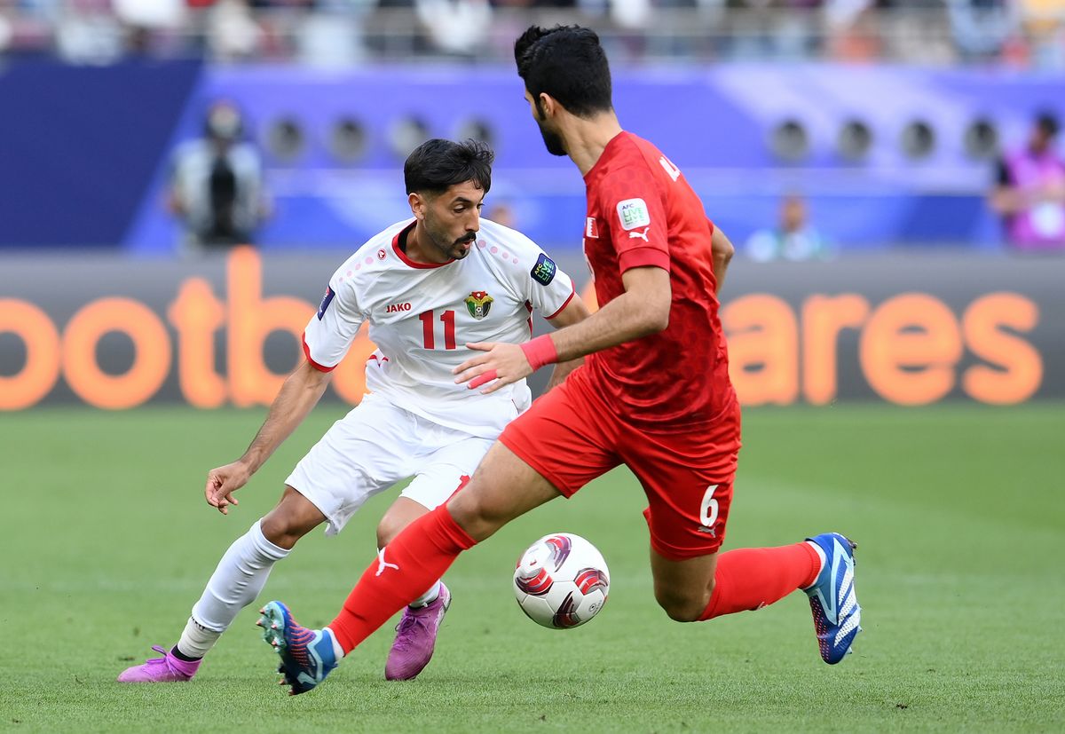 DOHA, QATAR - JANUARY 25: Yazan Al-Naimat of Jordan runs with the ball whilst under pressure from Mohamed Al-Hardan of Bahrain during the AFC Asian Cup Group E match between Jordan and Bahrain at Khalifa International Stadium on January 25, 2024 in Doha, Qatar. (Photo by Adam Nurkiewicz/Getty Images)